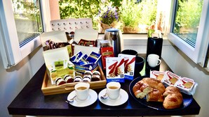 Un safata de petitdejuni amb pastissos, cafè i productes envasellats damunt d'una taula al costat d'una finestra que donava a vegetació.