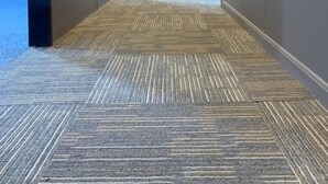Un long couloir étroit, doté d’un sol recouvert de moquette et de murs peints dans une couleur claire.