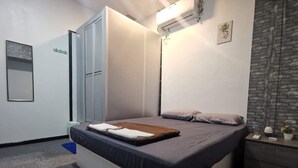 Une chambre à coucher avec un lit, une armoire, un bureau et une petite plante.