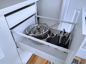 A kitchen drawer with a pot, a colander, and a set of knives. - Cozy Studio with Kitchenette Attached (Davenport)