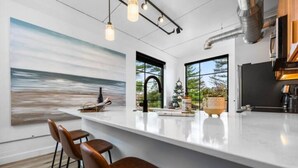 Une cuisine moderne dotée d’un grand îlot central, de tabourets de bar et offrant une vue sur l’extérieur.