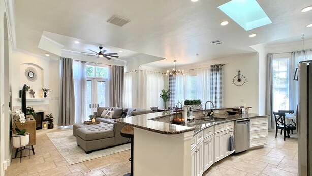 A spacious kitchen with a large island, a dining area, and a living room with a fireplace. - New Vista | Chef Kitchen, Golf Course Views (San Antonio)
