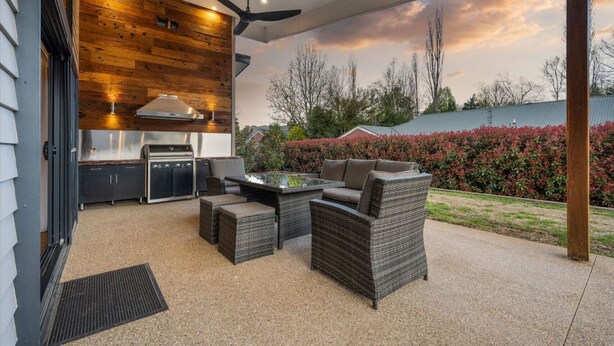 Un patio al aire libre con una parrilla, asientos y vistas al jardín.