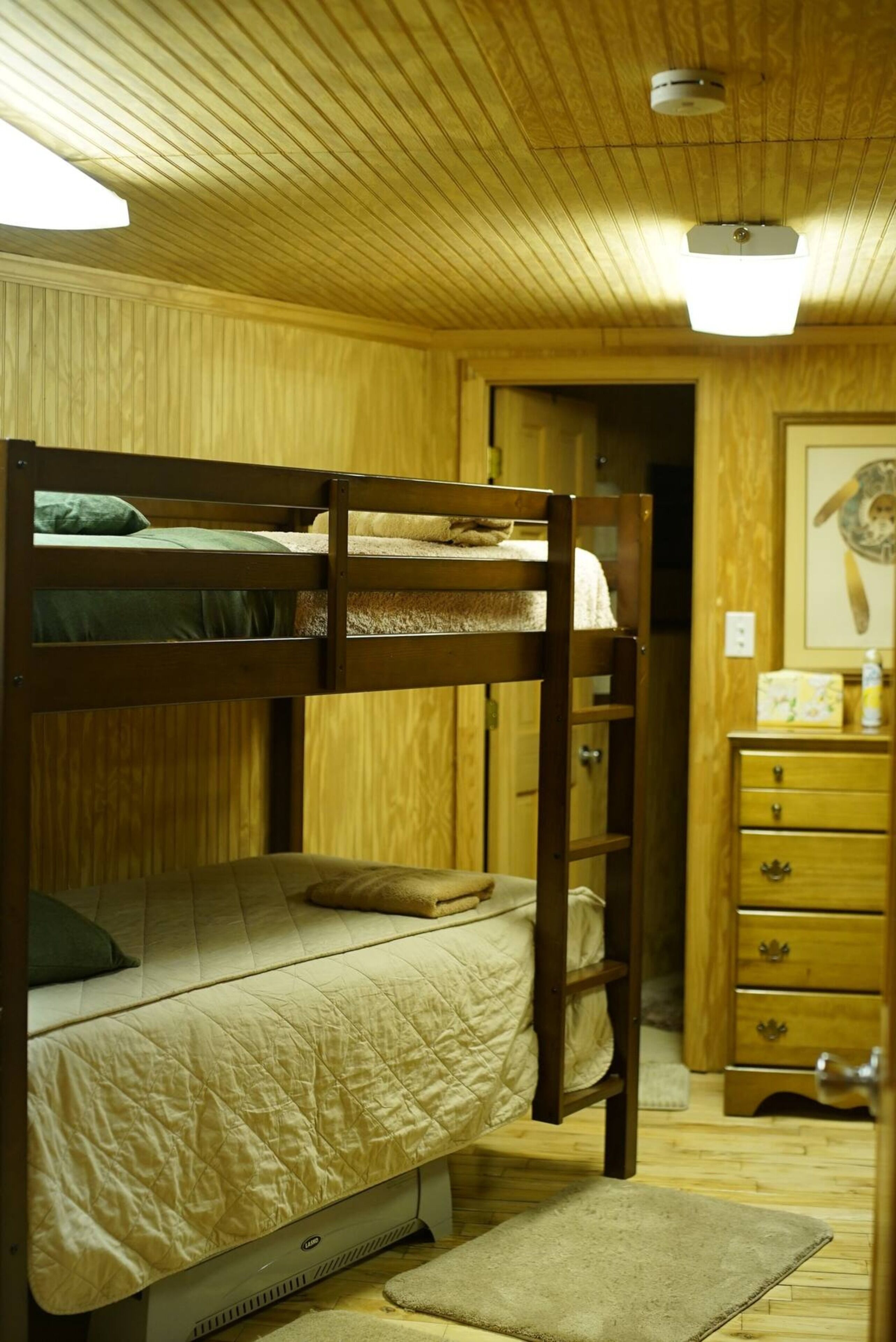 Camera con letto a castello, pareti in legno e ventilatore a soffitto.