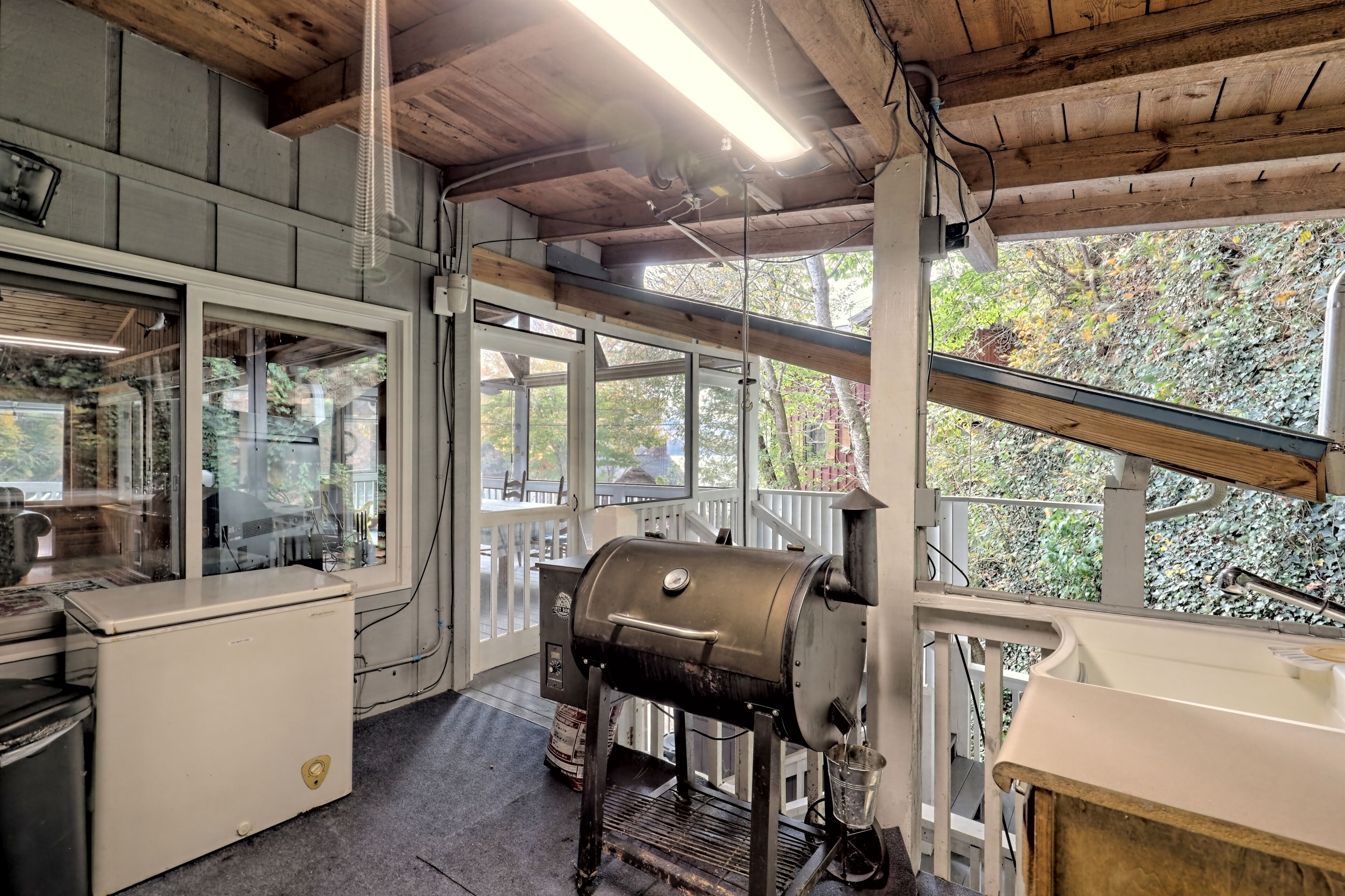 A kitchen with a built-in grill, a refrigerator, and a sink.
