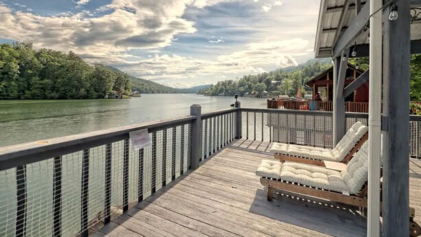 A wooden deck with lounge chairs overlooking a river, surrounded by greenery and a cloudy sky. - T Landing Top & Bottom Units (Clayton)