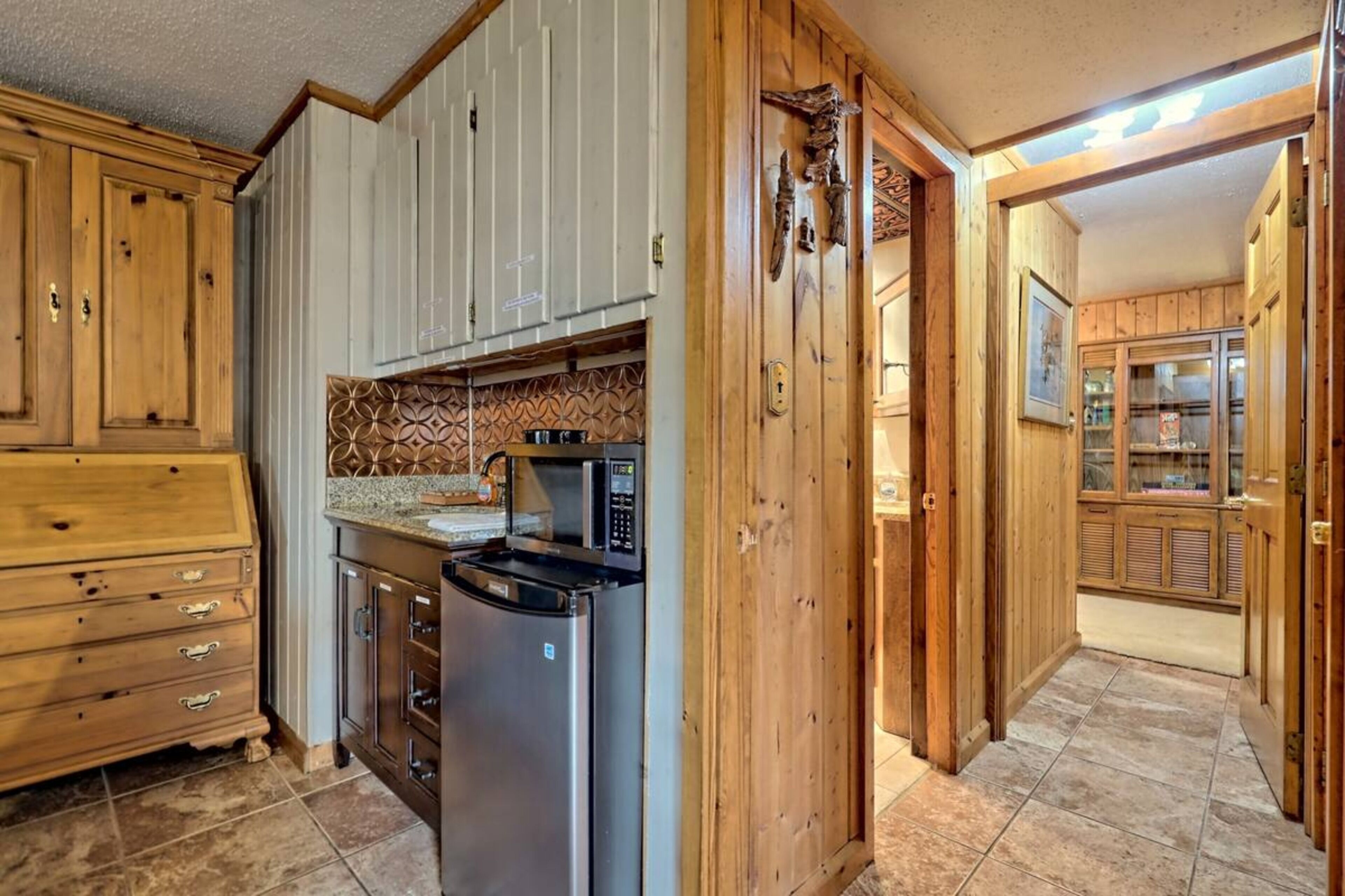 A kitchen with wooden cabinets, a stainless steel refrigerator, and a microwave.