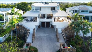 A modern two-story house with a central courtyard, surrounded by lush greenery and palm trees. - Chic Beachside Abode, Sunrise Beach (Sunrise Beach)