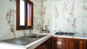 Eine Küche mit Marmorfliesenspiegel, Holzschränken, einer Spüle mit zwei Becken und einem Gasherd.