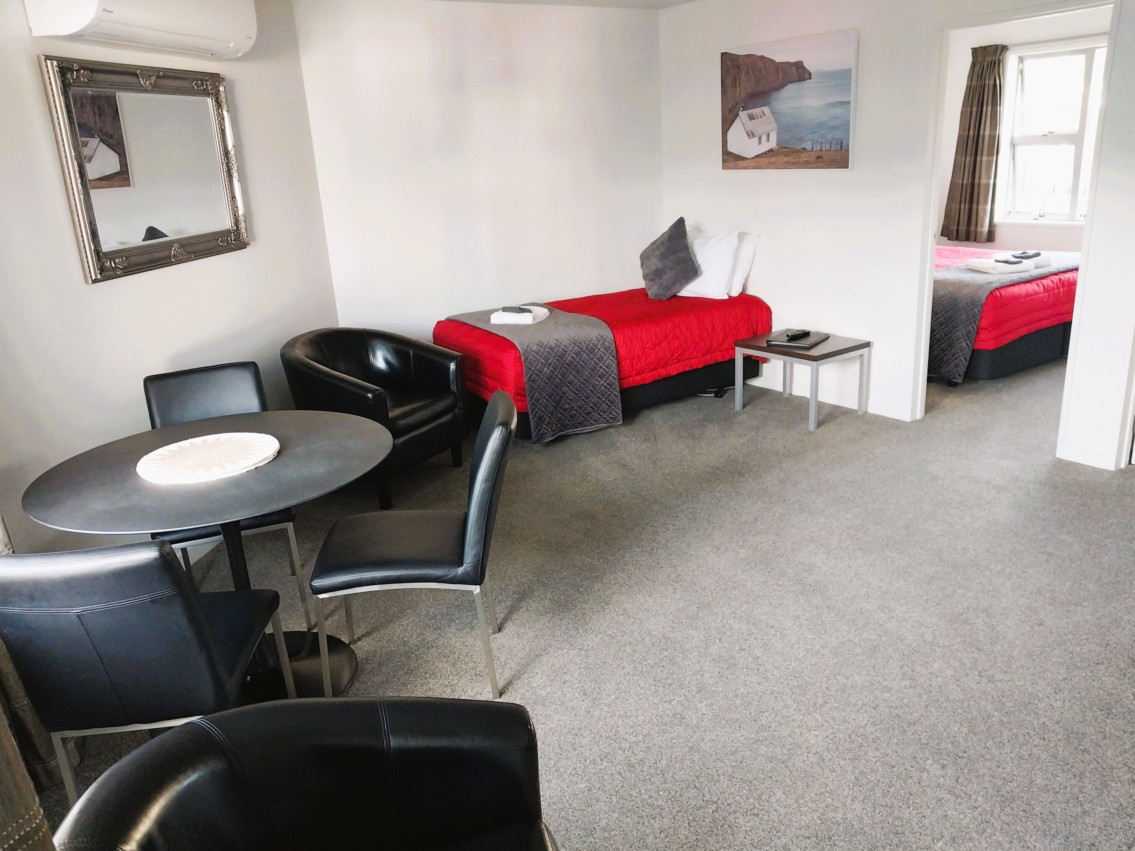 A hotel room with a bed, a desk, a chair, and a table.