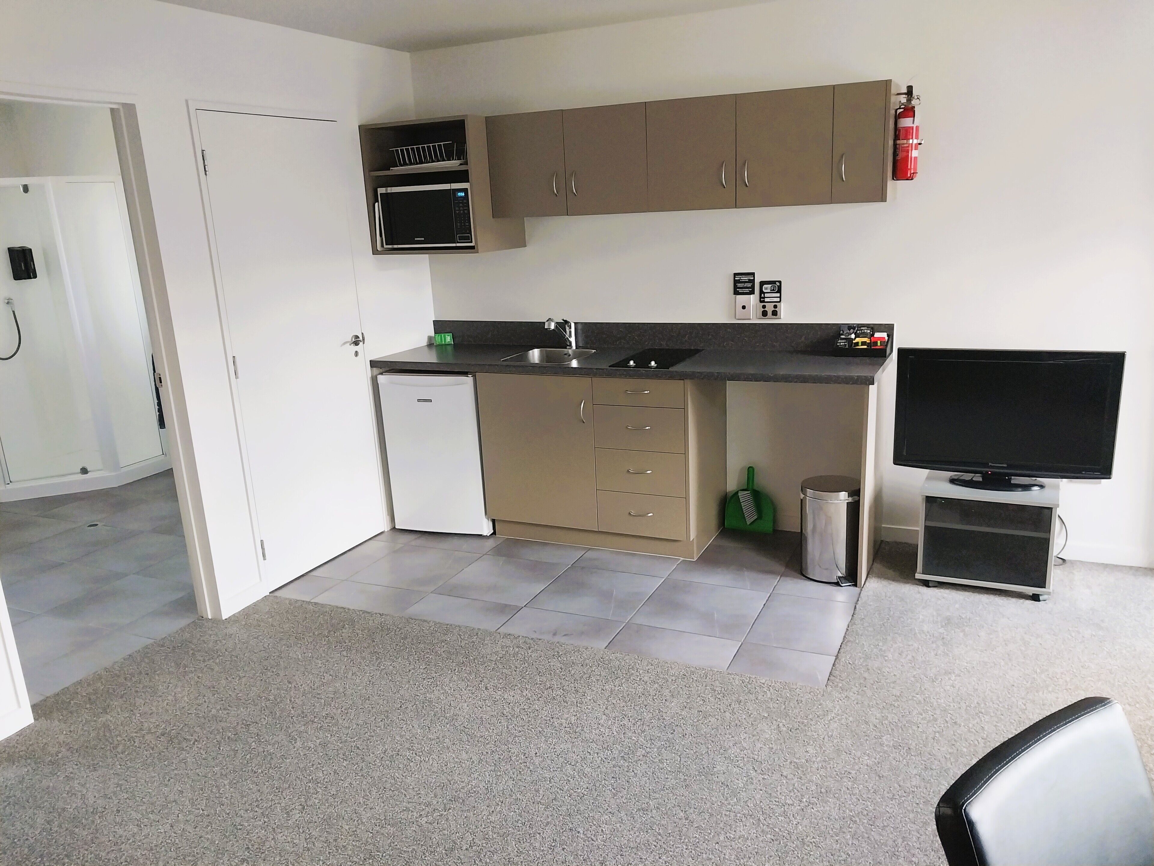 A compact kitchen with a microwave, sink, and a television.