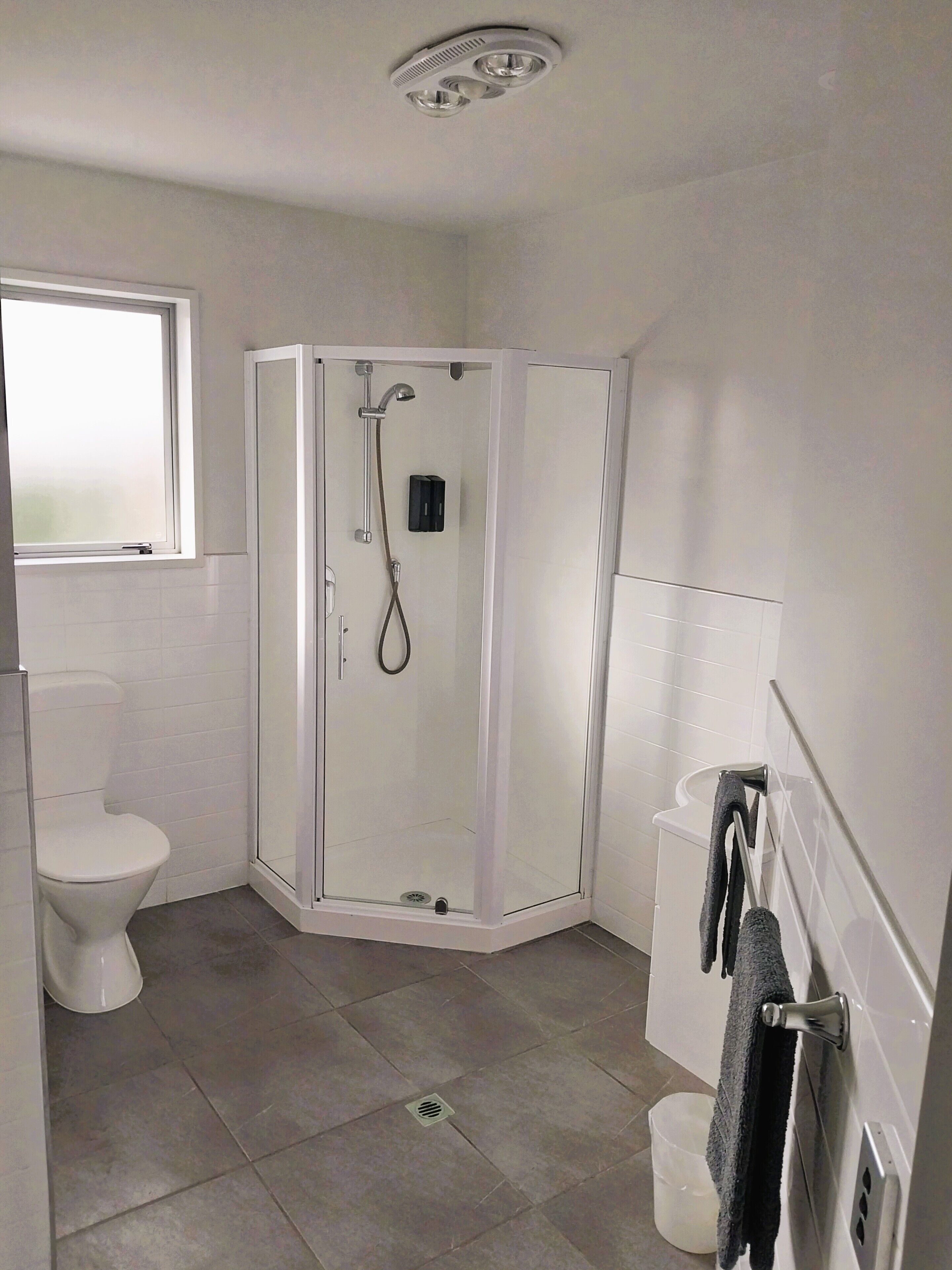 A bathroom with a toilet, a shower enclosure, and a sink.