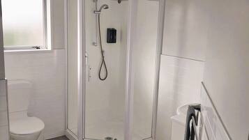 A bathroom with a toilet, a shower enclosure, and a sink.