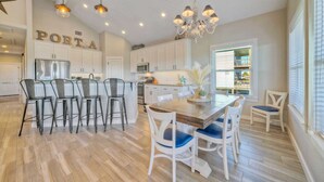 A modern kitchen with white cabinets, stainless steel appliances, and a central island with bar stools. - Private Pool Retreat Walk to Beach 2 Living Spaces + Game Room for Groups (Port Aransas)