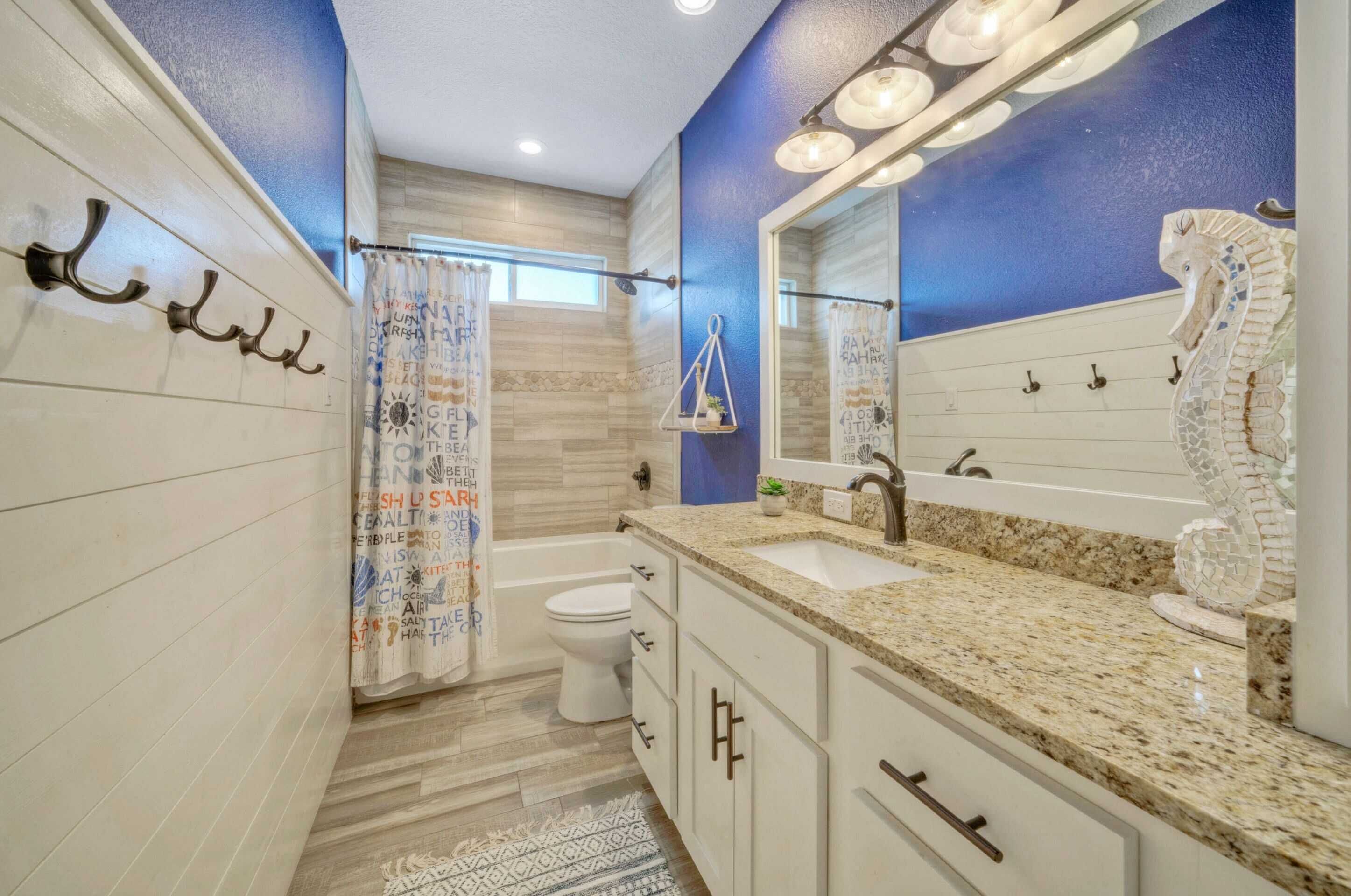 A modern bathroom with a large mirror, a bathtub, and a toilet.