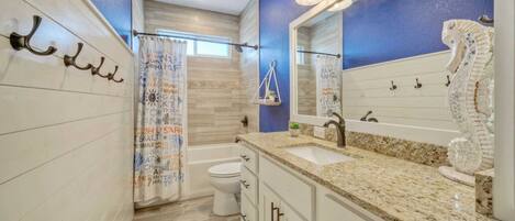 A modern bathroom with a large mirror, a bathtub, and a toilet.