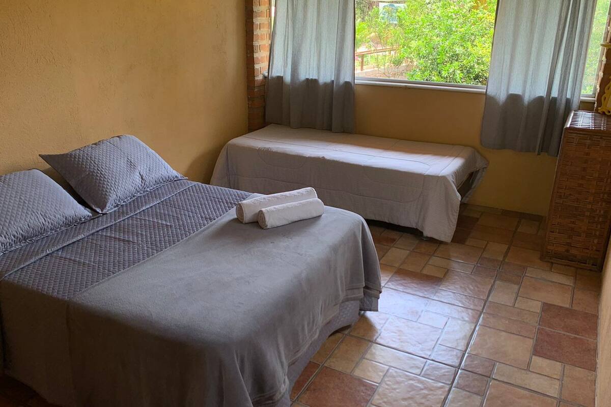 Una habitación con dos camas, una pared de ladrillo y una ventana con cortinas.