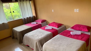 A room with four beds, each with a pink and beige bedspread, and a window with curtains. - Airpoint Pousada Ecológica (Lençóis)