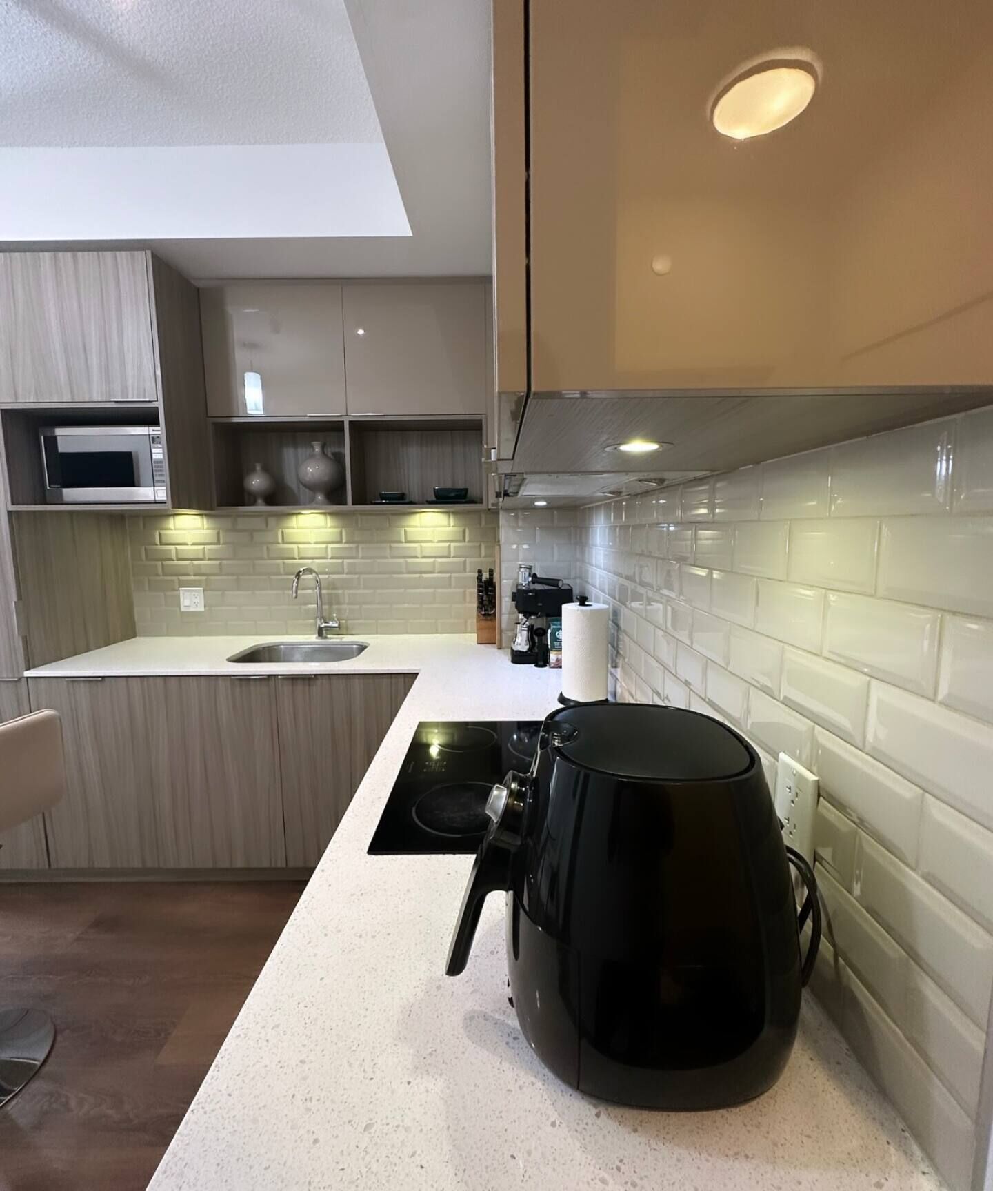 Una cocina moderna con microondas integrado, cafetera y lavamanos.