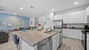 A modern kitchen with white cabinets, granite countertops, stainless steel appliances, and a central island with seating. - ⭐⭐⭐⭐⭐Spacious 10-BR Family Retreat Near Disney, Solterra Resort - Pool Spa, Game (Davenport)