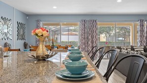 A dining area with a long table set with blue bowls and plates, a vase with flowers, and a decorative wall piece. - ⭐⭐⭐⭐⭐Spacious 10-BR Family Retreat Near Disney, Solterra Resort - Pool Spa, Game (Davenport)