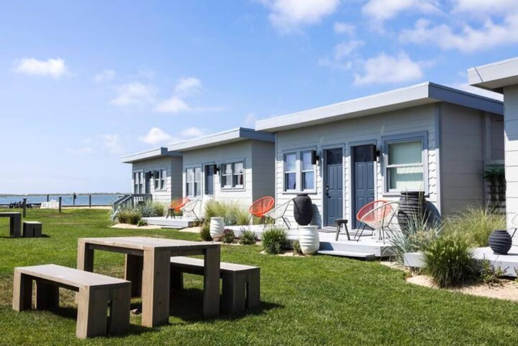 A modern building with a flat roof, large windows, and a grassy lawn with outdoor seating.