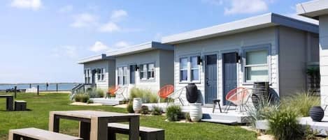 A modern building with a flat roof, large windows, and a grassy lawn with outdoor seating.