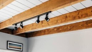 Une chambre à coucher avec un lit, des poutres en bois, une fenêtre et une table de chevet.
