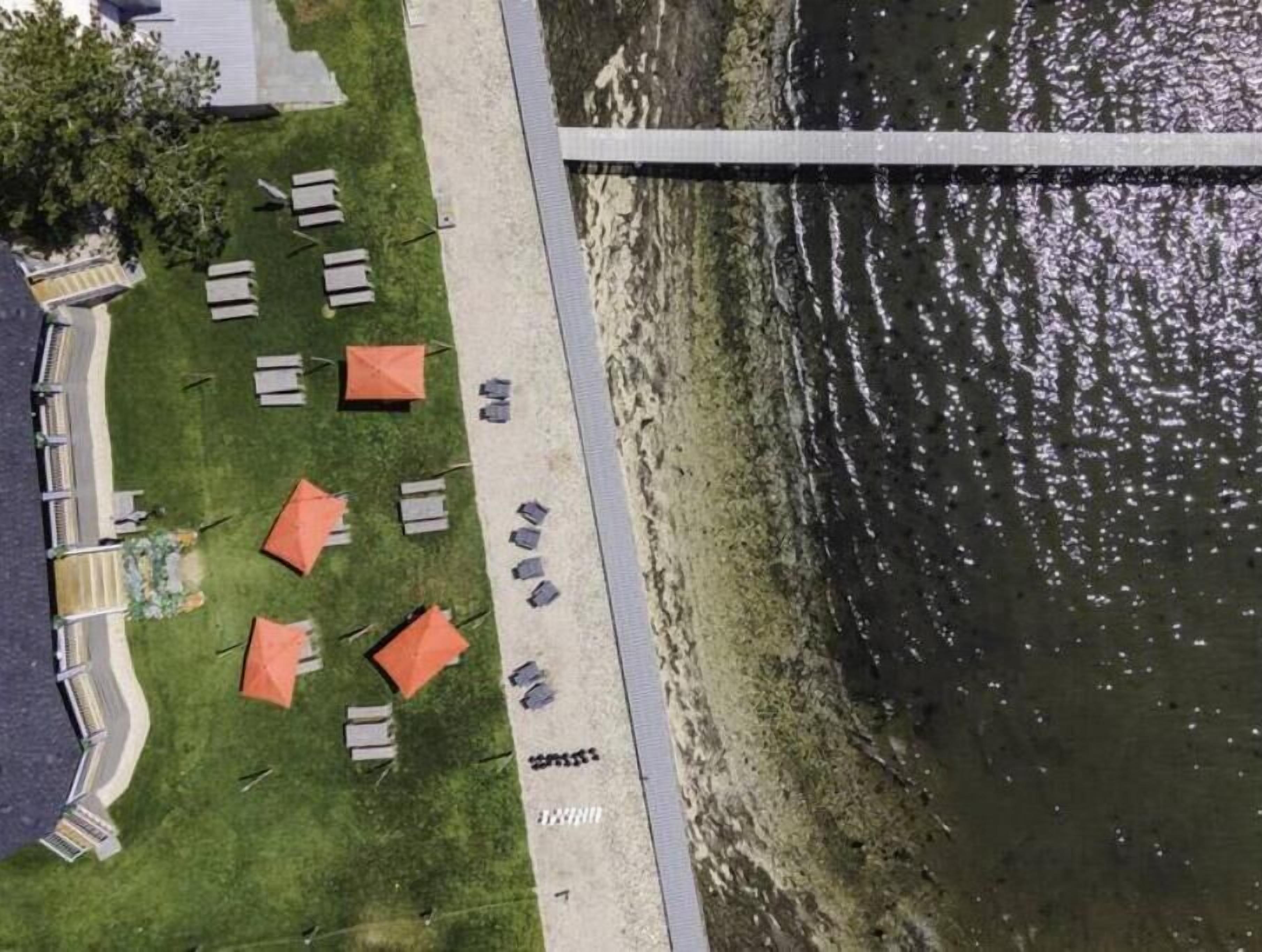 Vista aérea de un hotel a la orilla del río con asientos al aire libre y un puente.