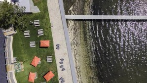 Vista aérea de un hotel a la orilla del río con asientos al aire libre y un puente.