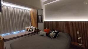 A modern bedroom with a large window, a bedside table with a lamp, and a bed with decorative pillows. - Living (Poços de Caldas)