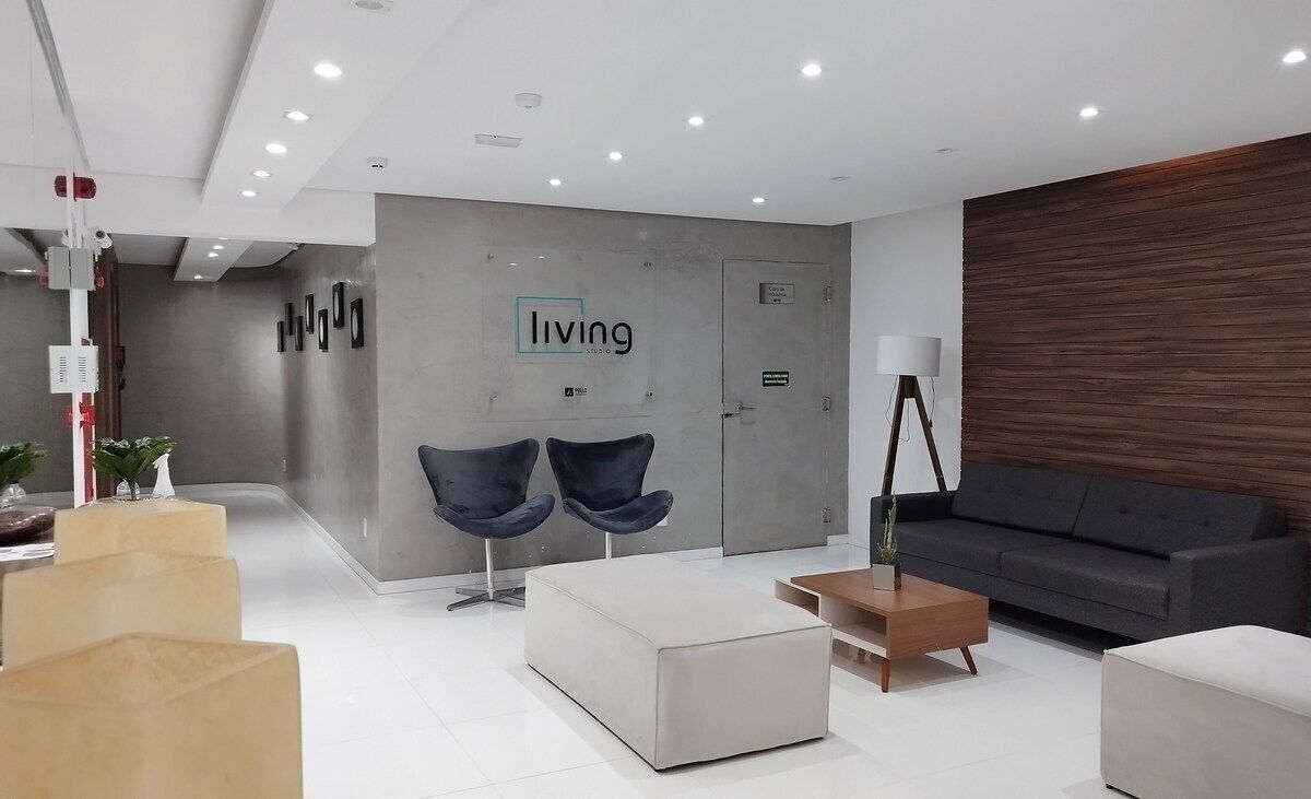 A modern reception area with a 'living' sign, two blue chairs, a sofa, and a lamp.