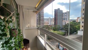A balcony with a view of a cityscape, including tall buildings and greenery. - Living (Poços de Caldas)