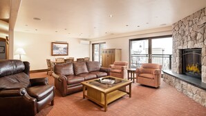 A spacious living room with leather sofas, a glass coffee table, and a stone fireplace. - North Of Nell, Unit 4b (Aspen)