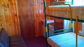 A bunk bed room with a wooden ceiling, a sofa, and a door. - Hostal Gomero (Santa Cruz)