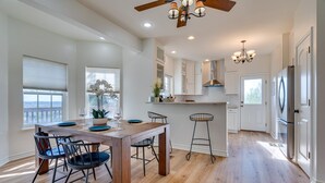 A modern kitchen with wooden flooring, white cabinets, a central island, and bar stools. - Jonestown Retreat w/ Deck: 6 Mi to Lake Travis! (Jonestown)