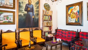 A room with wooden furniture, a bookshelf, and a large portrait. - Ciudadela el Artesano  (Carolina del Príncipe)