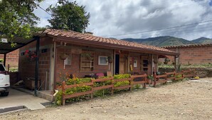 A rustic brick building with a tiled roof, a wooden fence, and a small garden area. - Ciudadela el Artesano  (Carolina del Príncipe)