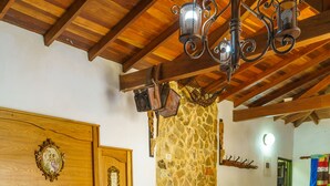 A bedroom with a wooden headboard, a stone fireplace, a sofa, and a bed with a colorful quilt. - Ciudadela el Artesano  (Carolina del Príncipe)
