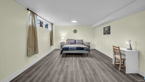 A bedroom with a bed, bedside tables, a desk with a chair, and a window with curtains. - Spacious 2 Bedroom Guest Suite in North York (Toronto)