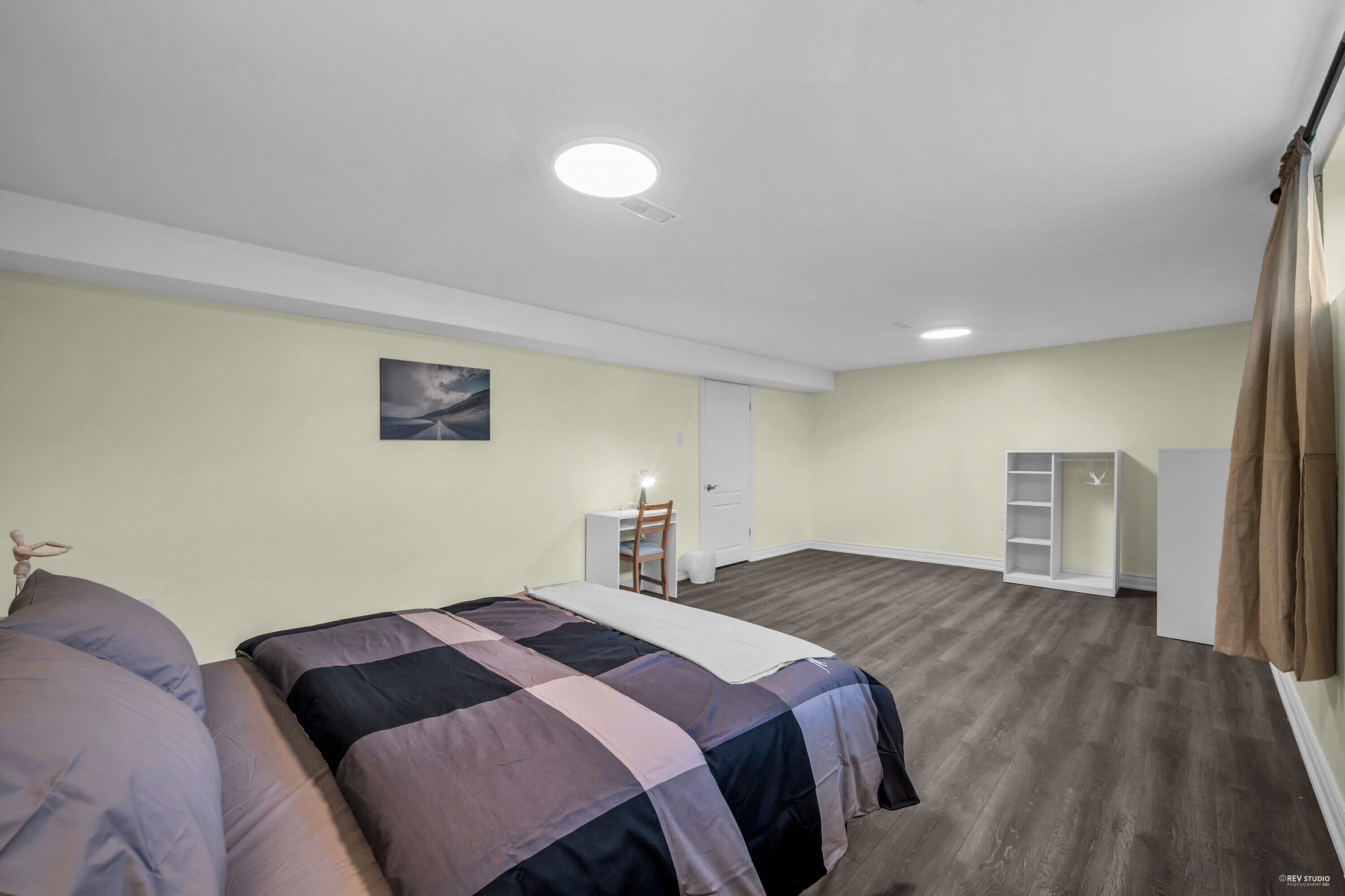 Ett sovrum med två sängar, ett skrivbord, en stol, en garderob och en taklampa.