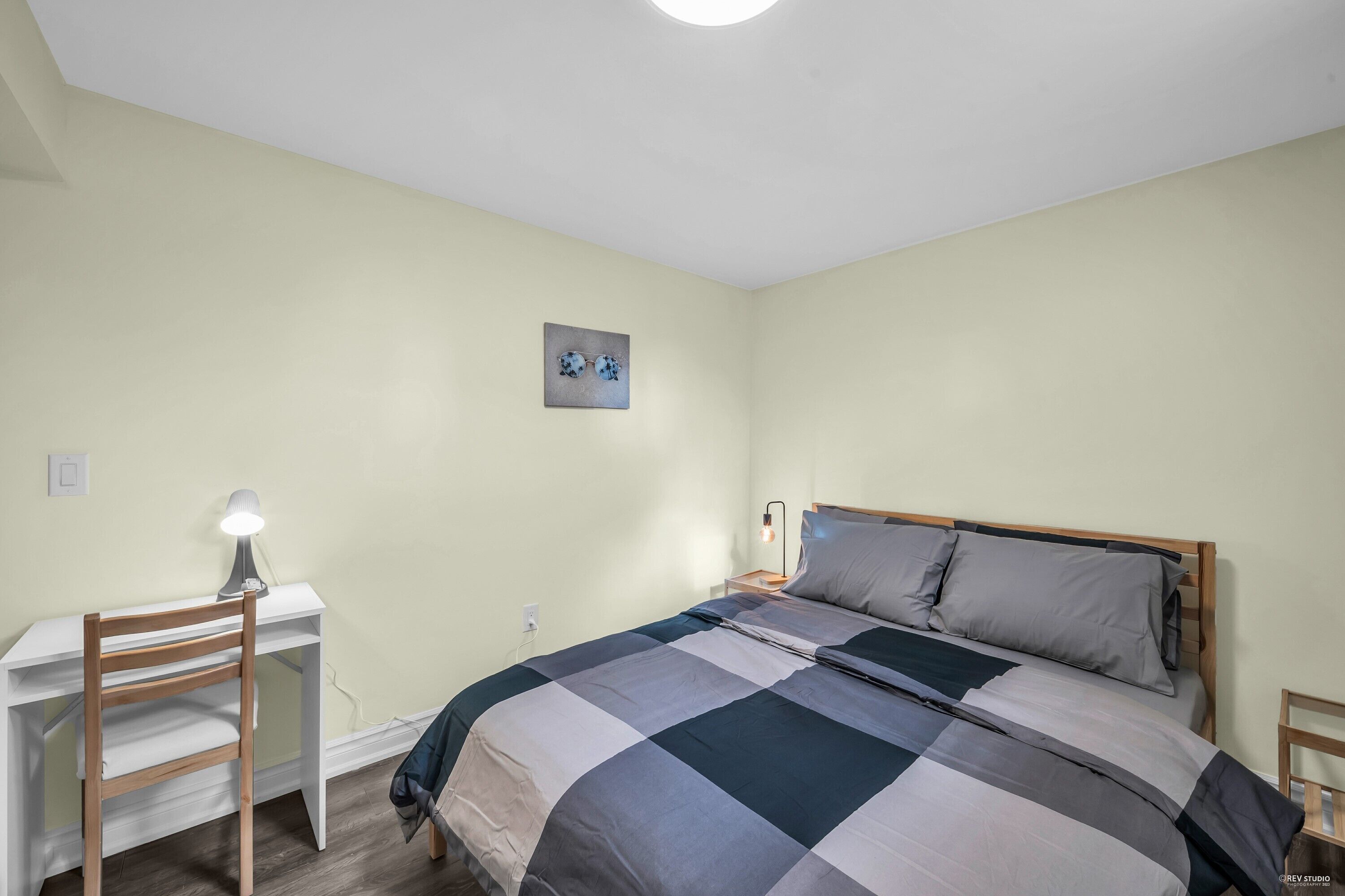 A bedroom with a bed, a desk, and a chair.