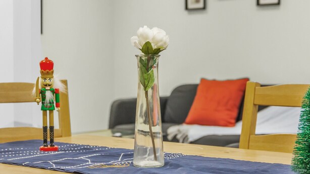 A nutcracker figurine and a vase with a white flower on a table in a room with a couch and framed pictures on the wall. - Spacious 2 Bedroom Guest Suite in North York (Toronto)