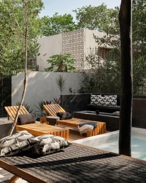 A poolside area with lounge chairs, a sofa, and a patterned wall.