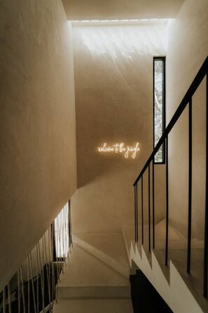 A staircase with a neon sign reading 'welcome to the jungle' and a window at the top.