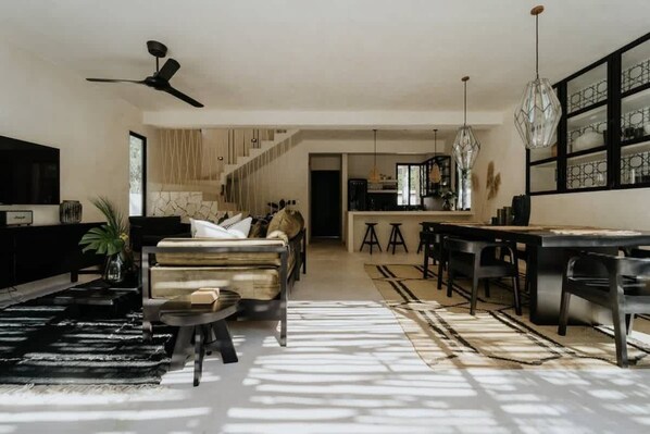 A spacious living area with a sofa, a dining table, and a kitchen in the background.