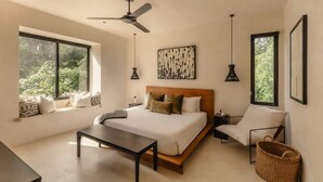 A modern bedroom with a large bed, a desk, a chair, and a ceiling fan.