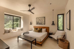 Un dormitorio moderno con una cama grande, un escritorio, una silla y un ventilador de techo.