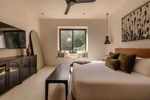 A bedroom with a bed, a desk, a cabinet, a ceiling fan, a window, and a painting on the wall.