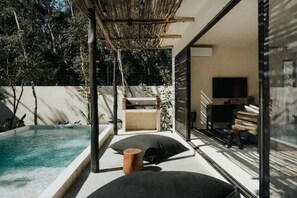 Un espacio exterior moderno con piscina, asientos y televisor.